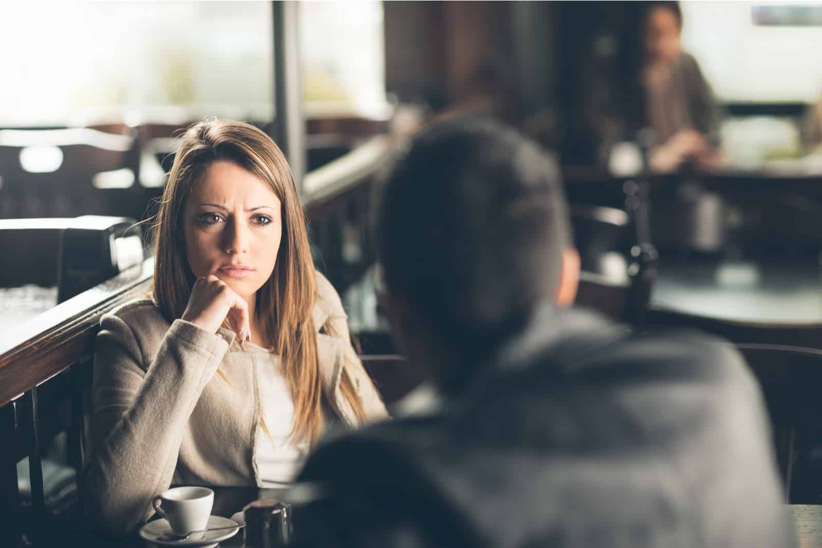 la femme regarde l'homme pendant qu'ils parlent et boivent du café