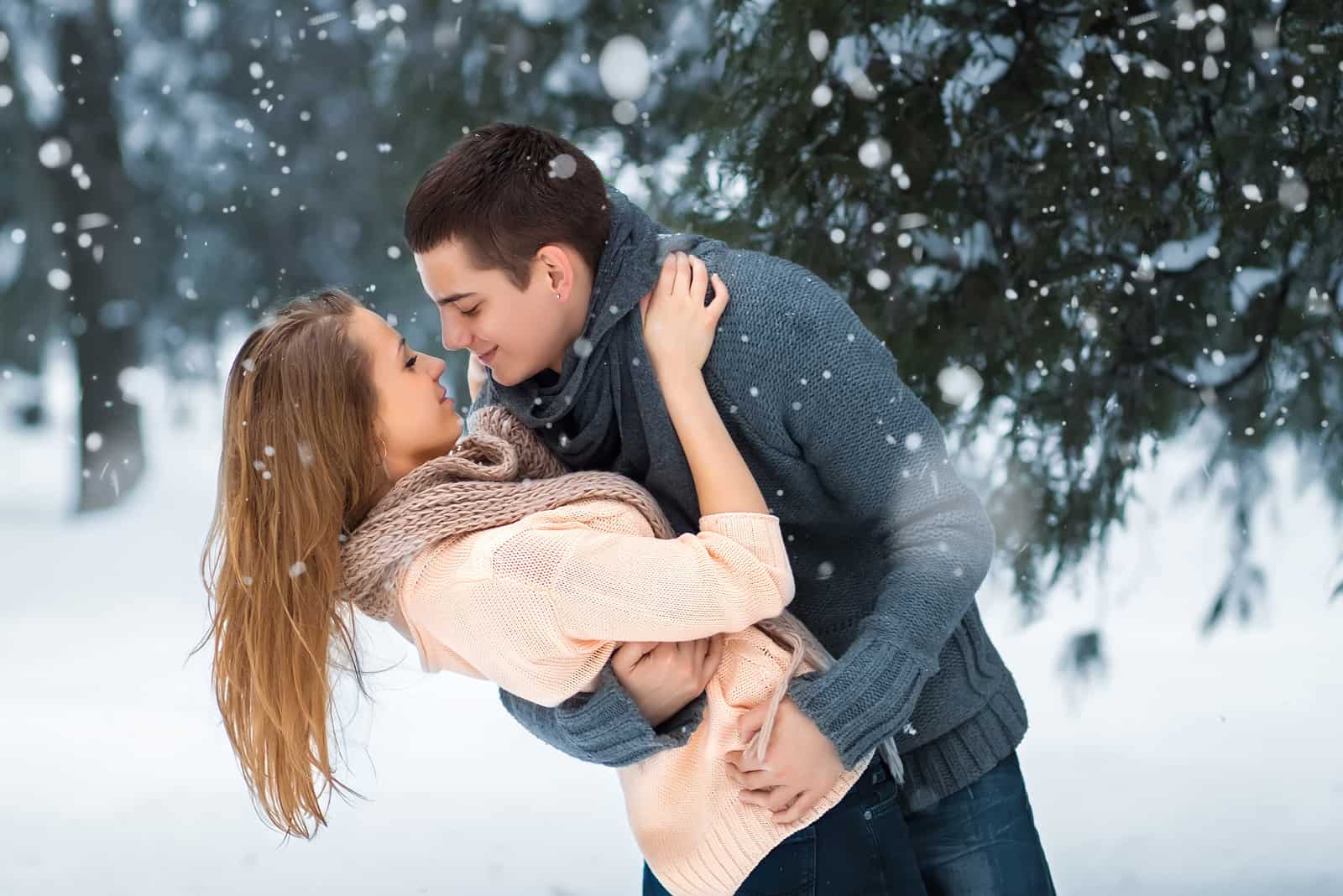 un couple heureux dehors dans la neige debout et étreignant