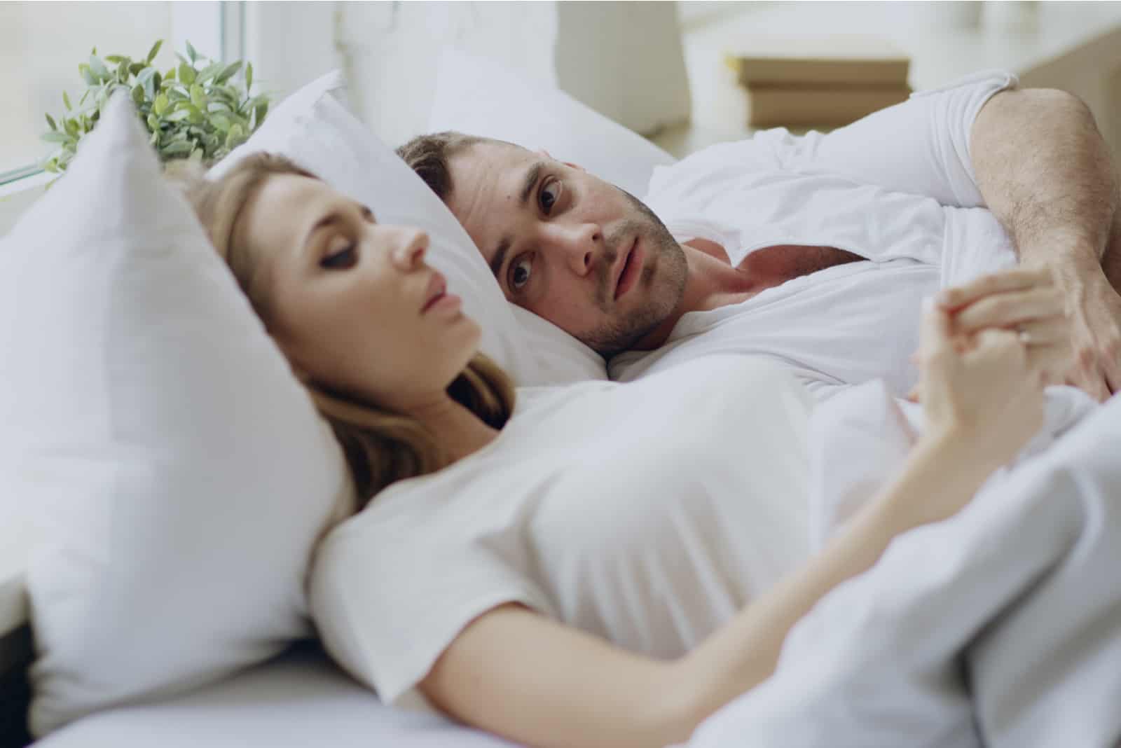 un homme et une femme parlent en position couchée dans son lit