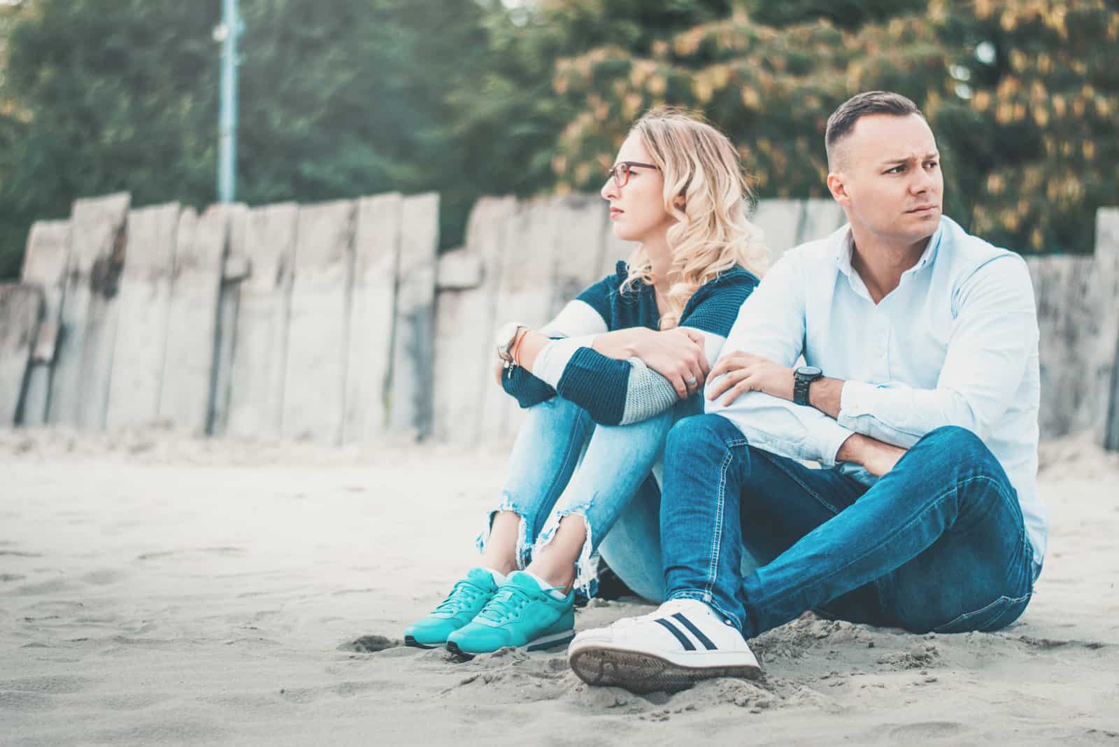 un homme et une femme sont assis sur la plage