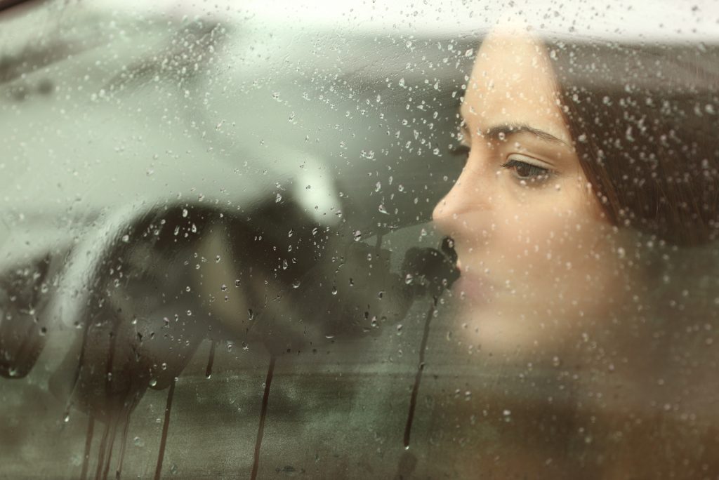 une fille triste regarde par la fenêtre de la voiture