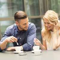 un homme et une femme riant et buvant du café