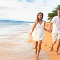 un homme et une femme traversent la plage