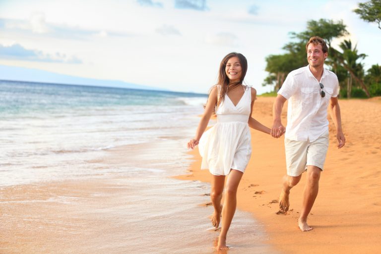 un homme et une femme traversent la plage