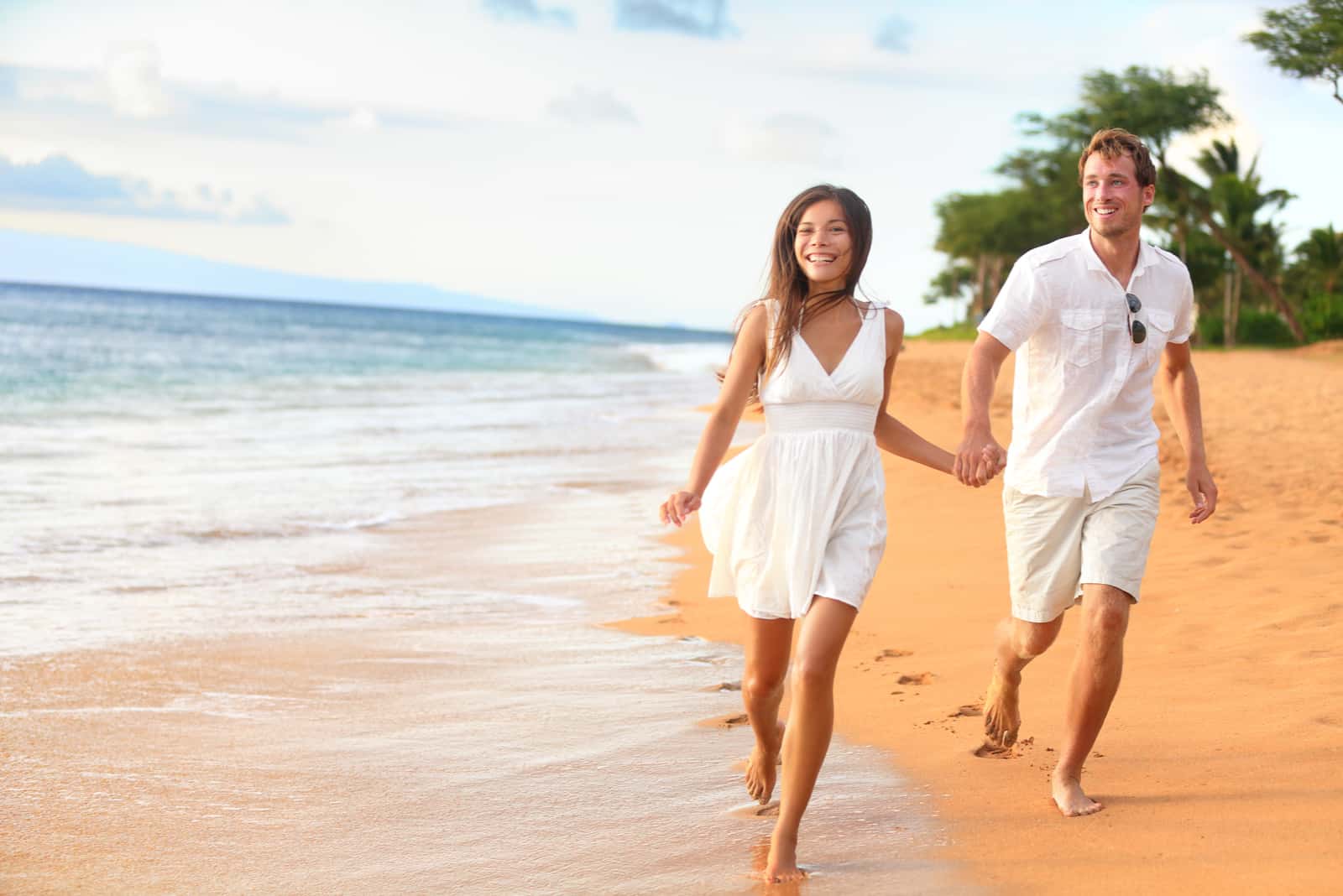 un homme et une femme traversent la plage