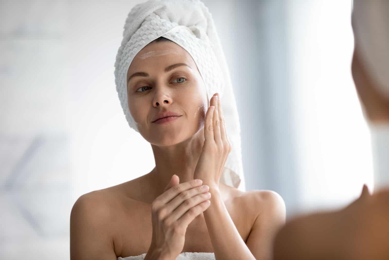 Belle femme paisible appliquant une crème hydratante sur la peau