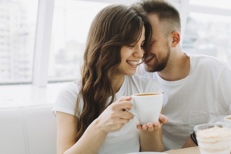 un homme et une femme buvant du café et riant