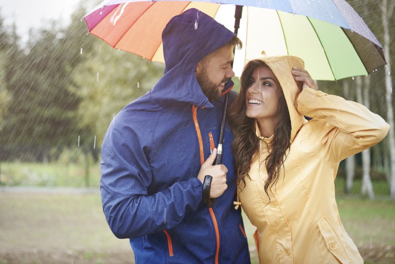 un homme et une femme riant sous des parapluies