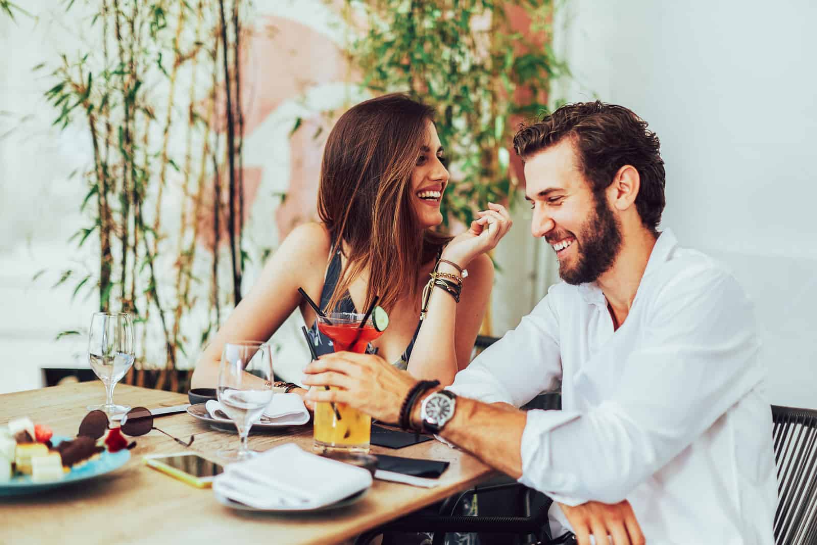 Jeune couple assis dans le bar extérieur et boire des cocktails