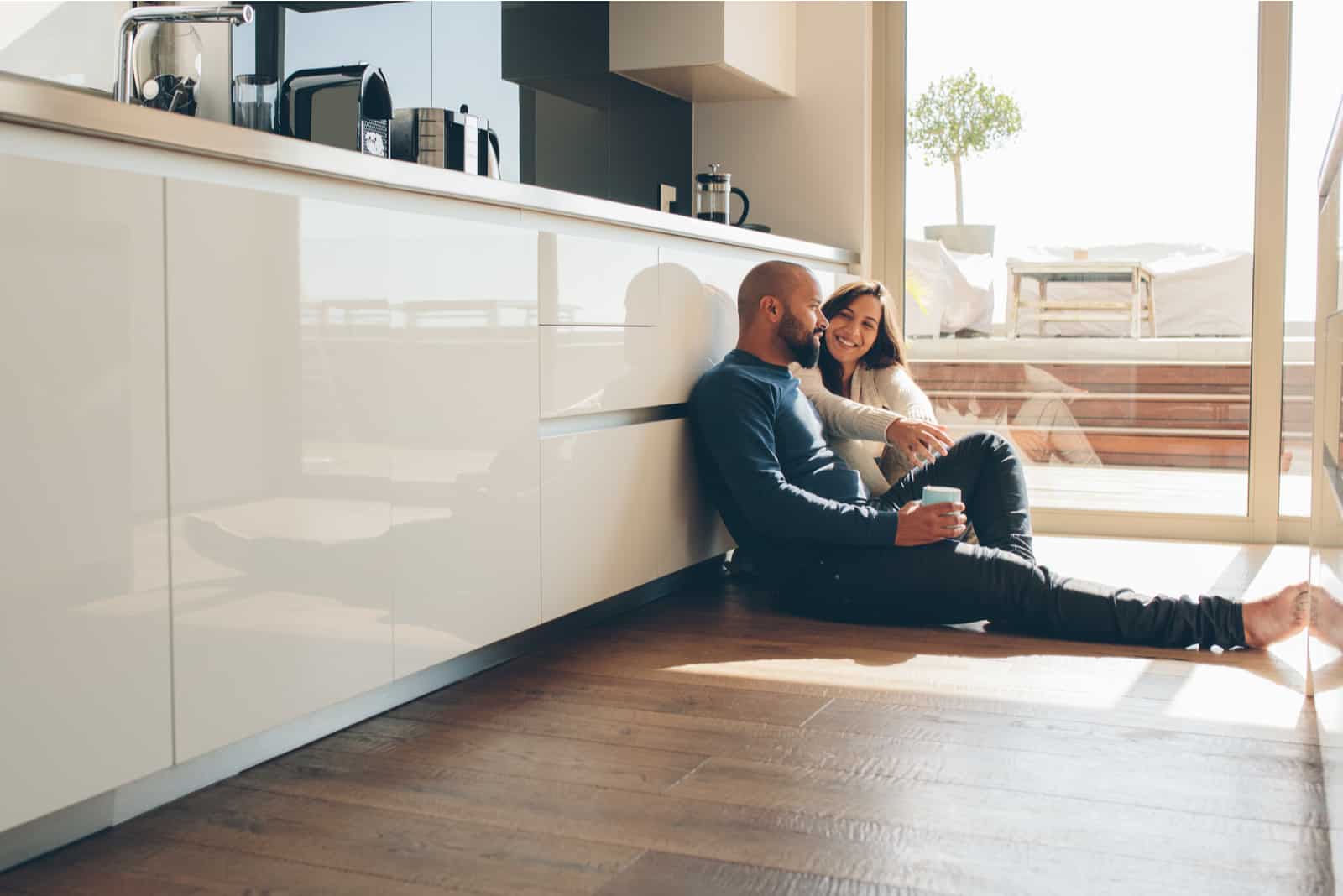 Jeune homme et femme assise sur le sol dans la cuisine et parler