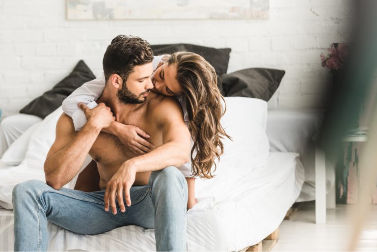 la femme a serré l'homme dans ses bras alors qu'il était assis sur le lit et l'a embrassé sur la joue
