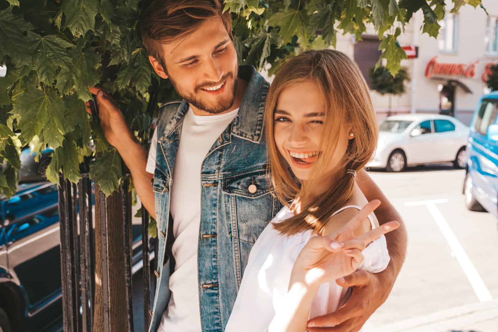 Sourire belle fille et son beau petit ami posant dans la rue près de larbre