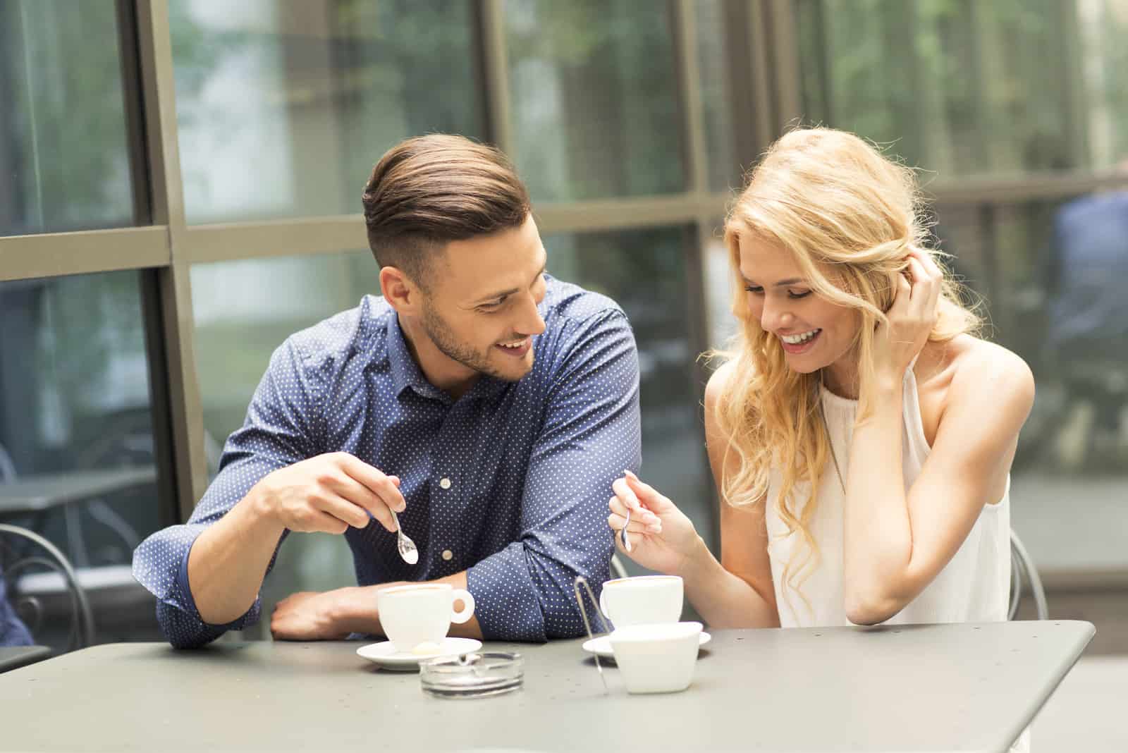 Un homme et une femme aux cheveux blonds buvant du café et riant