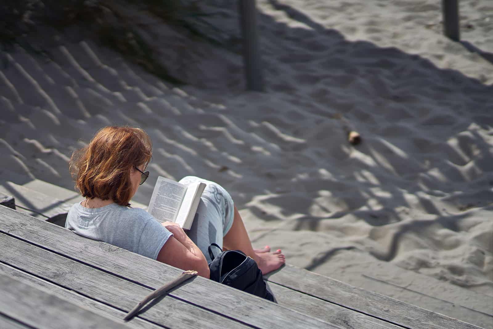 femme assise sur la plage lisant un livre