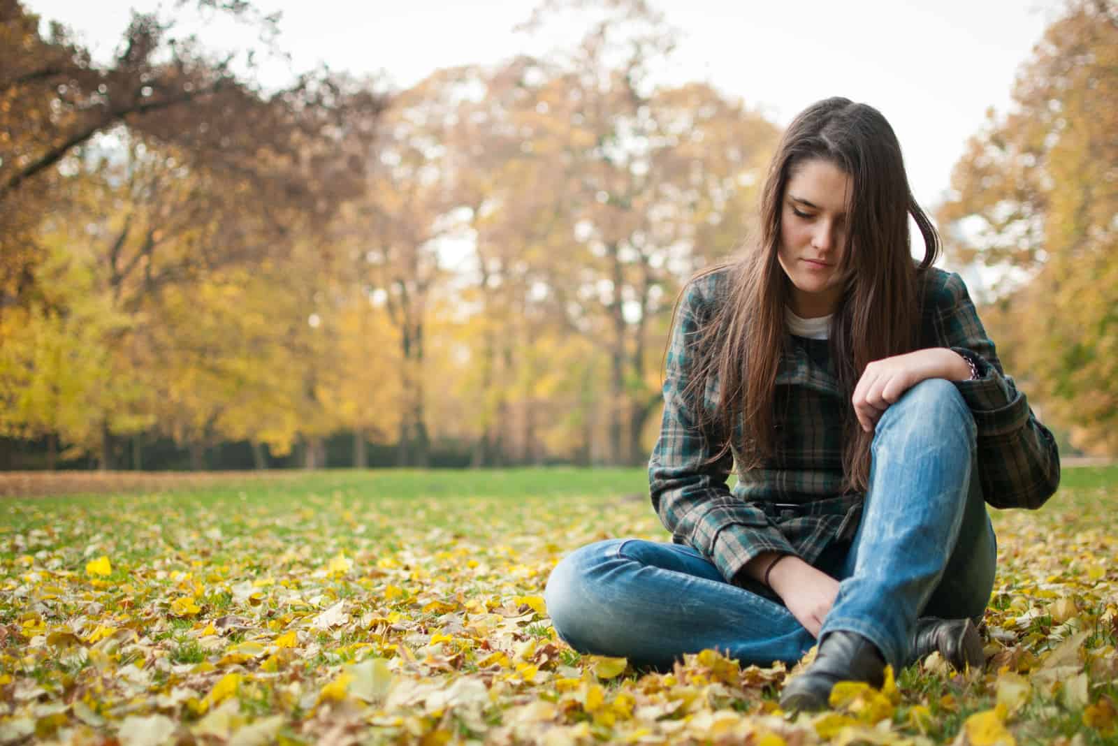 Triste femme seule assise sur le sol dans le parc