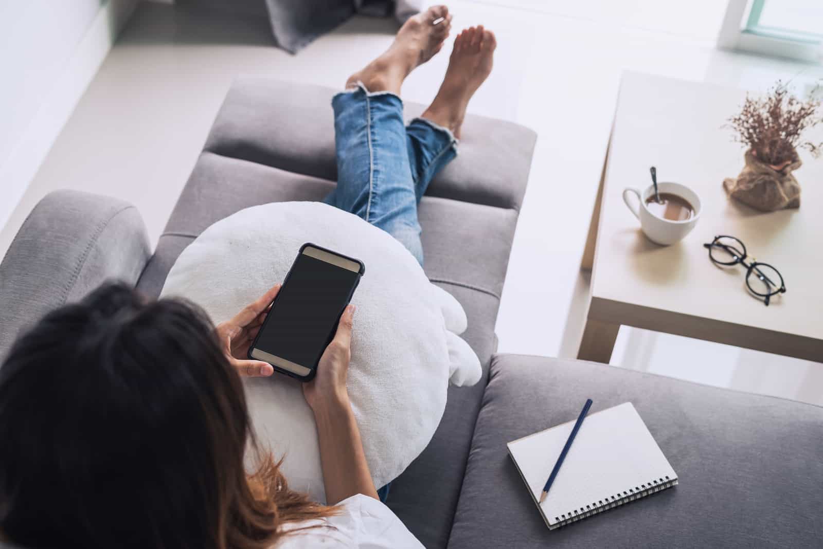 femme utilisant un smartphone et se détendre sur le canapé