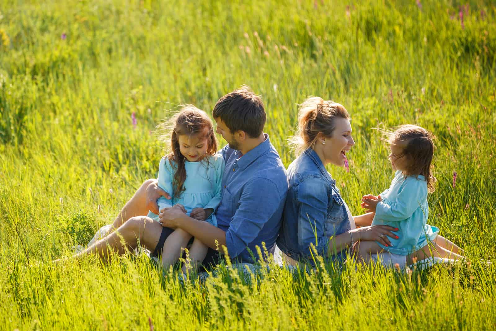 un homme et une femme assis sur l'herbe avec des enfants