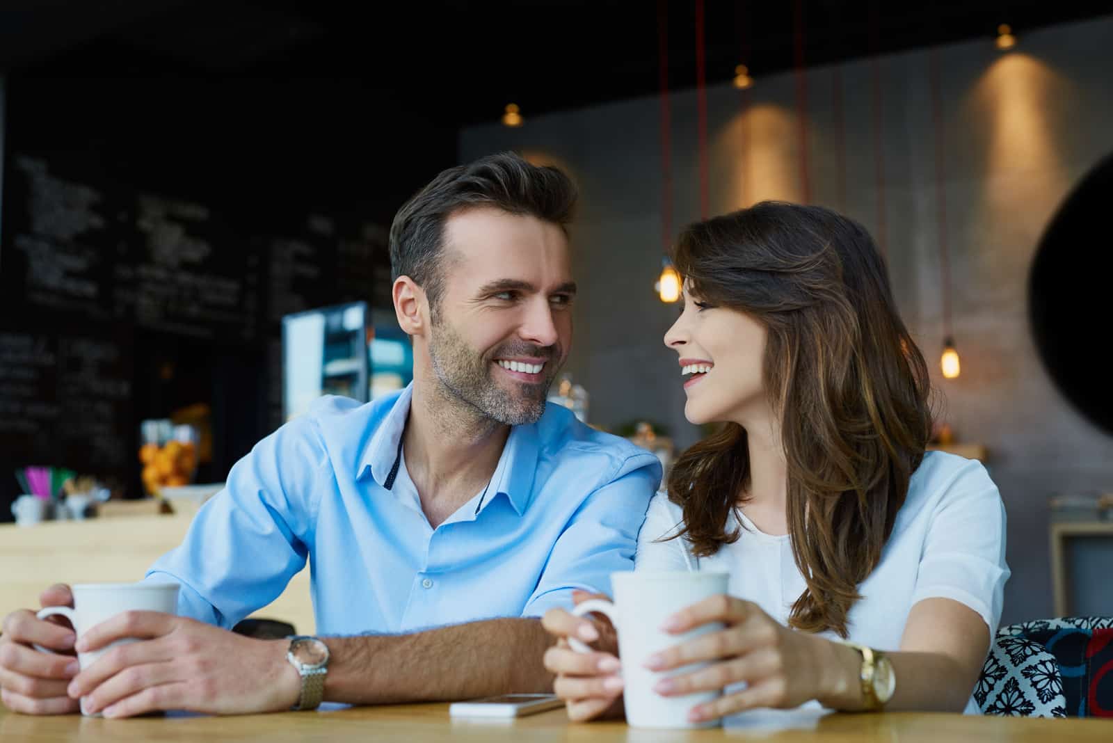un homme et une femme s'assoient à une table et rient