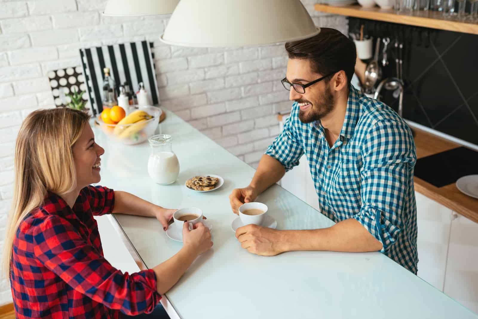 un homme et une femme sont assis à une table, buvant du café