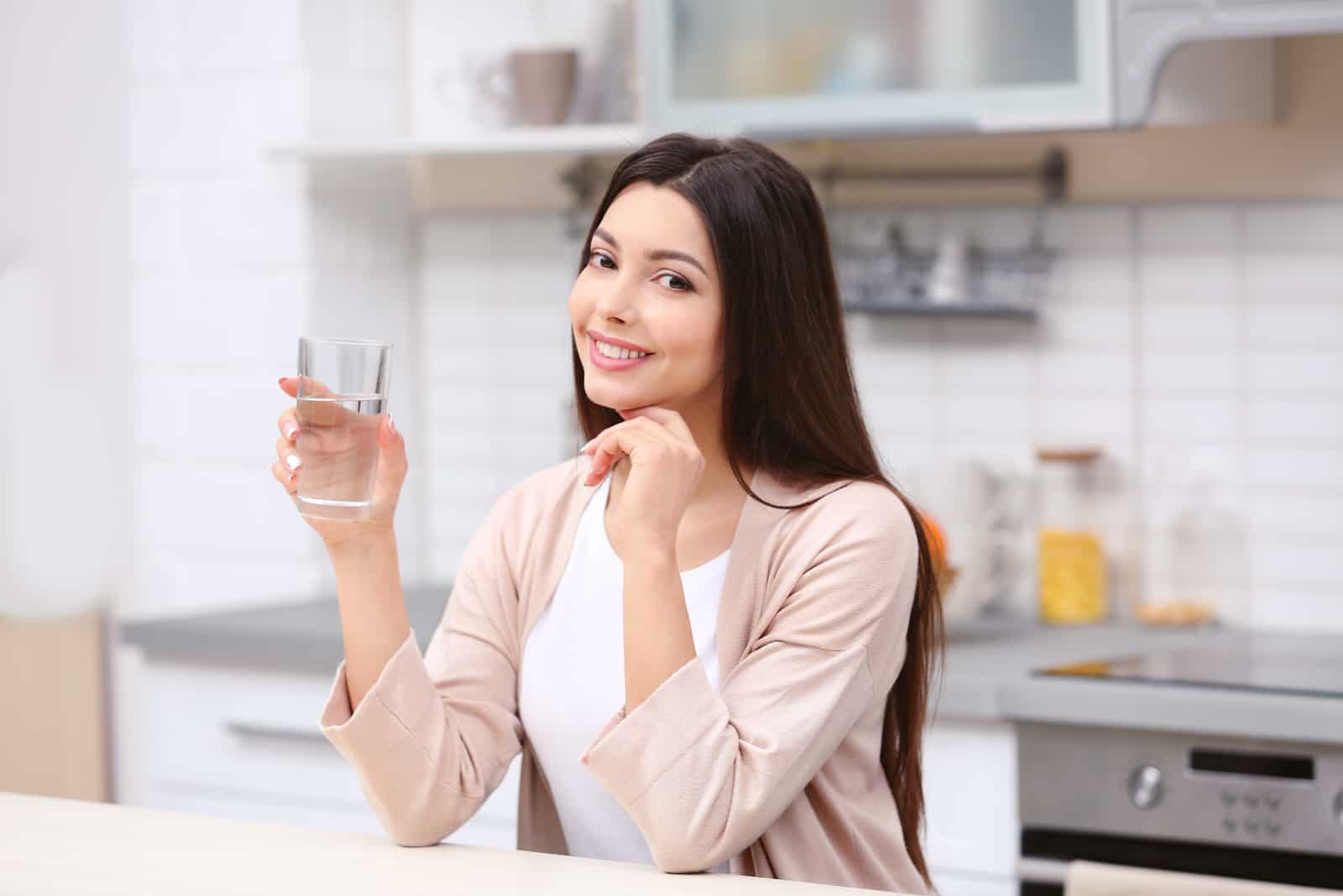 une femme aux longs cheveux noirs s'assoit et boit de l'eau
