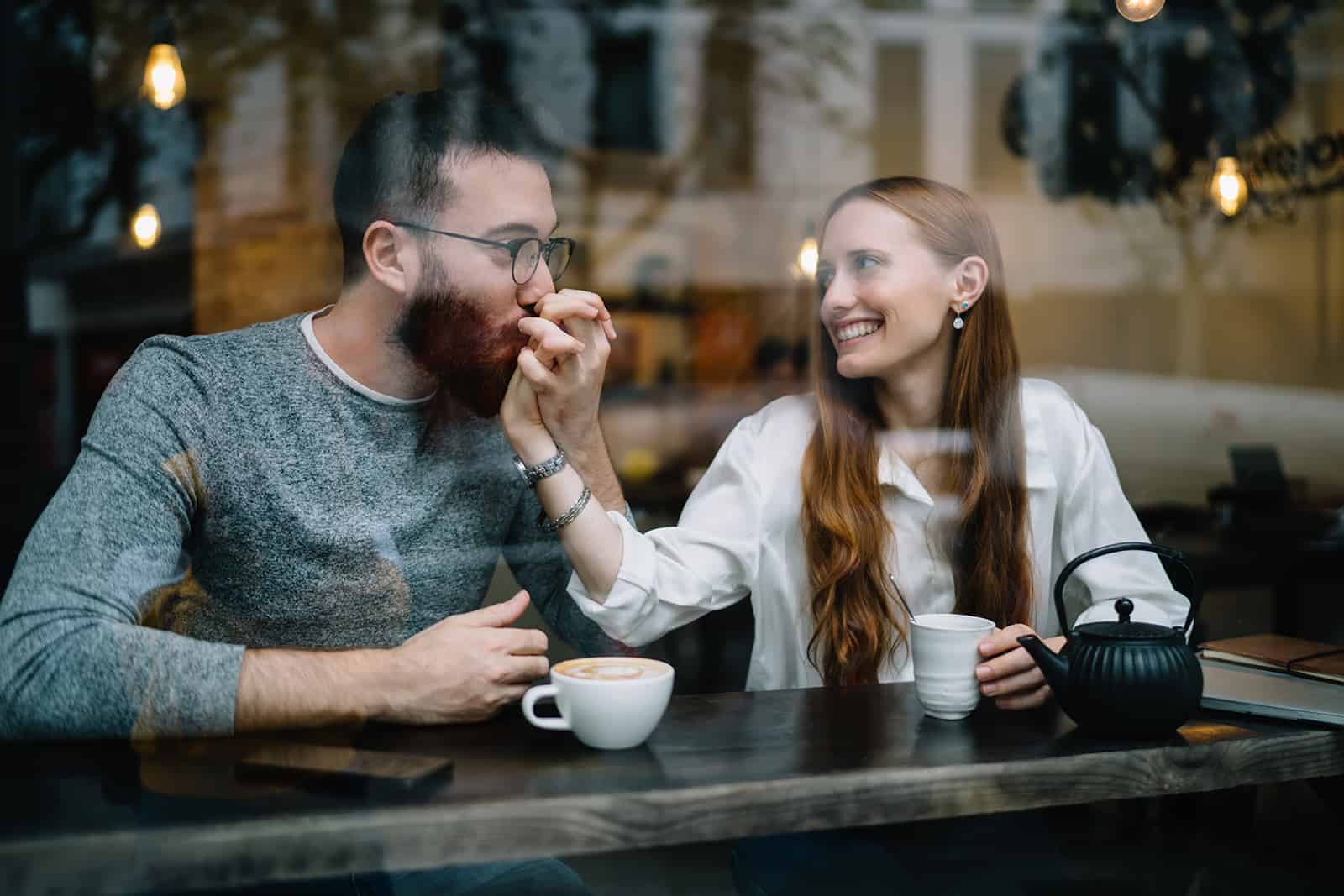 Aimer le jeune homme embrassant la main de la femme alors qu'il était assis ensemble dans le café