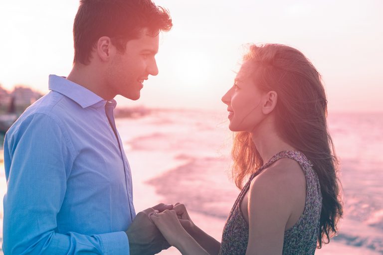 un couple main dans la main en se tenant debout sur la plage