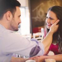 un homme touchant un visage de femme souriante dans le café