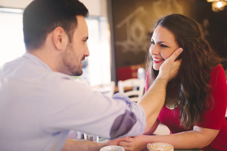 un homme touchant un visage de femme souriante dans le café