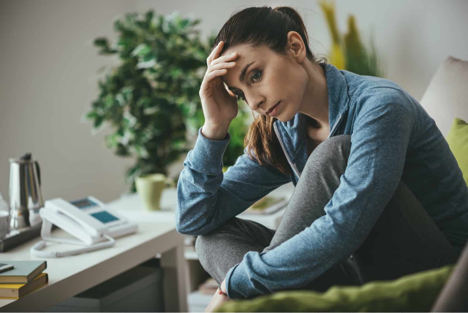 Femme déprimée triste à la maison assise sur le canapé
