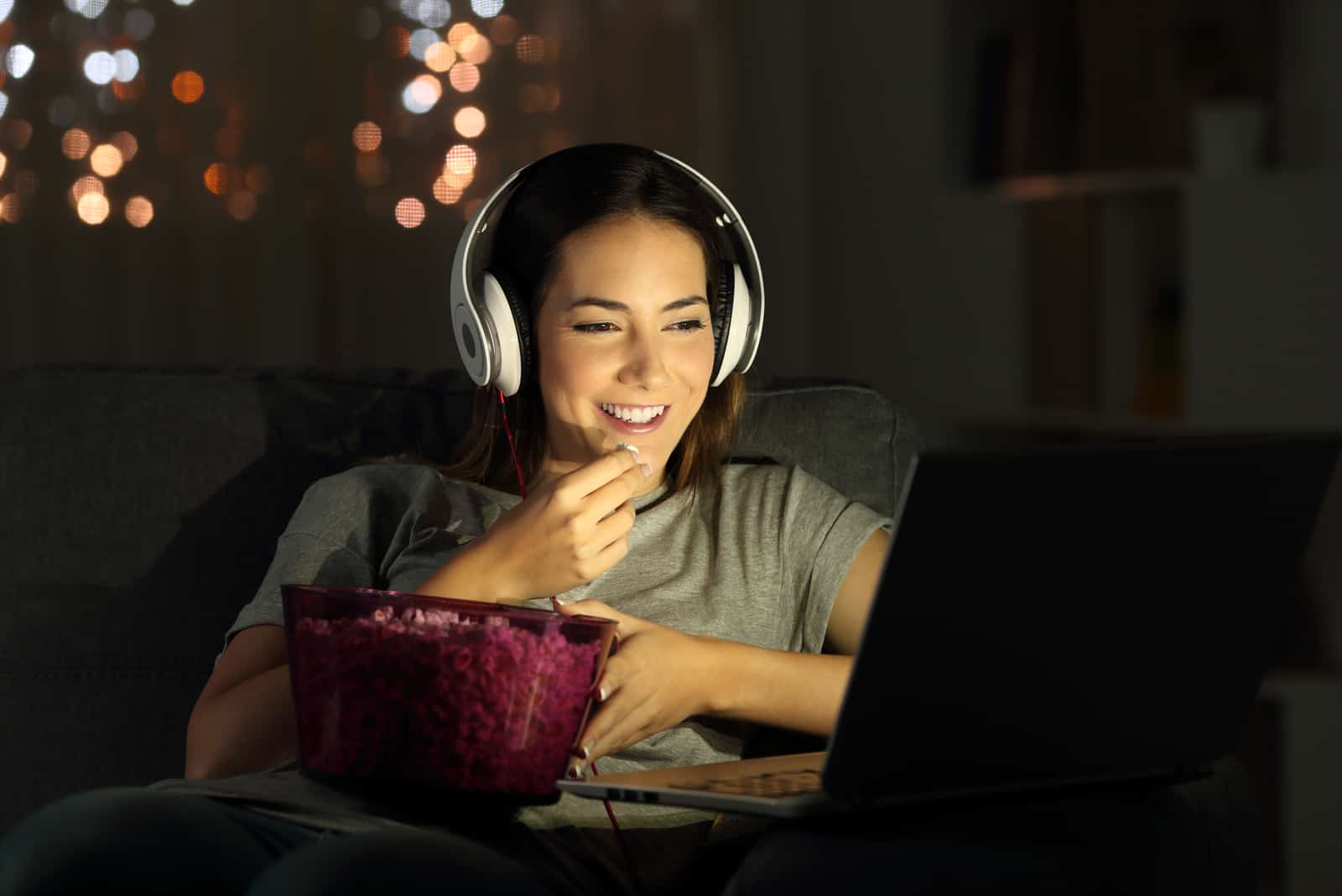 Femme regardant la télévision en ligne dans la nuit assis sur un canapé