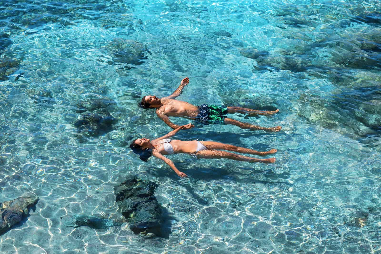 Heureux couple nageant dans la mer turquoise transparente.