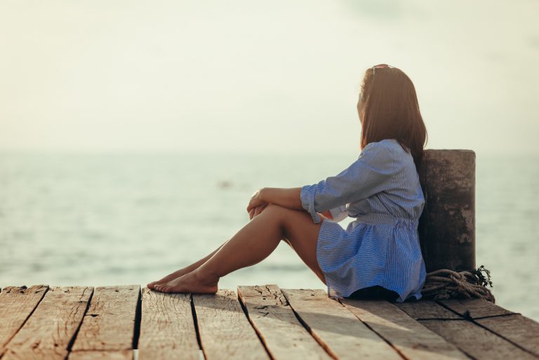 femme assise seule en regardant la mer