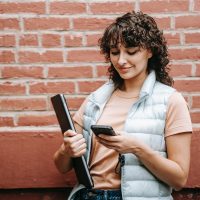Une femme souriante lisant un message texte sur le téléphone