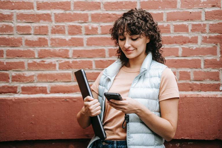 Une femme souriante lisant un message texte sur le téléphone