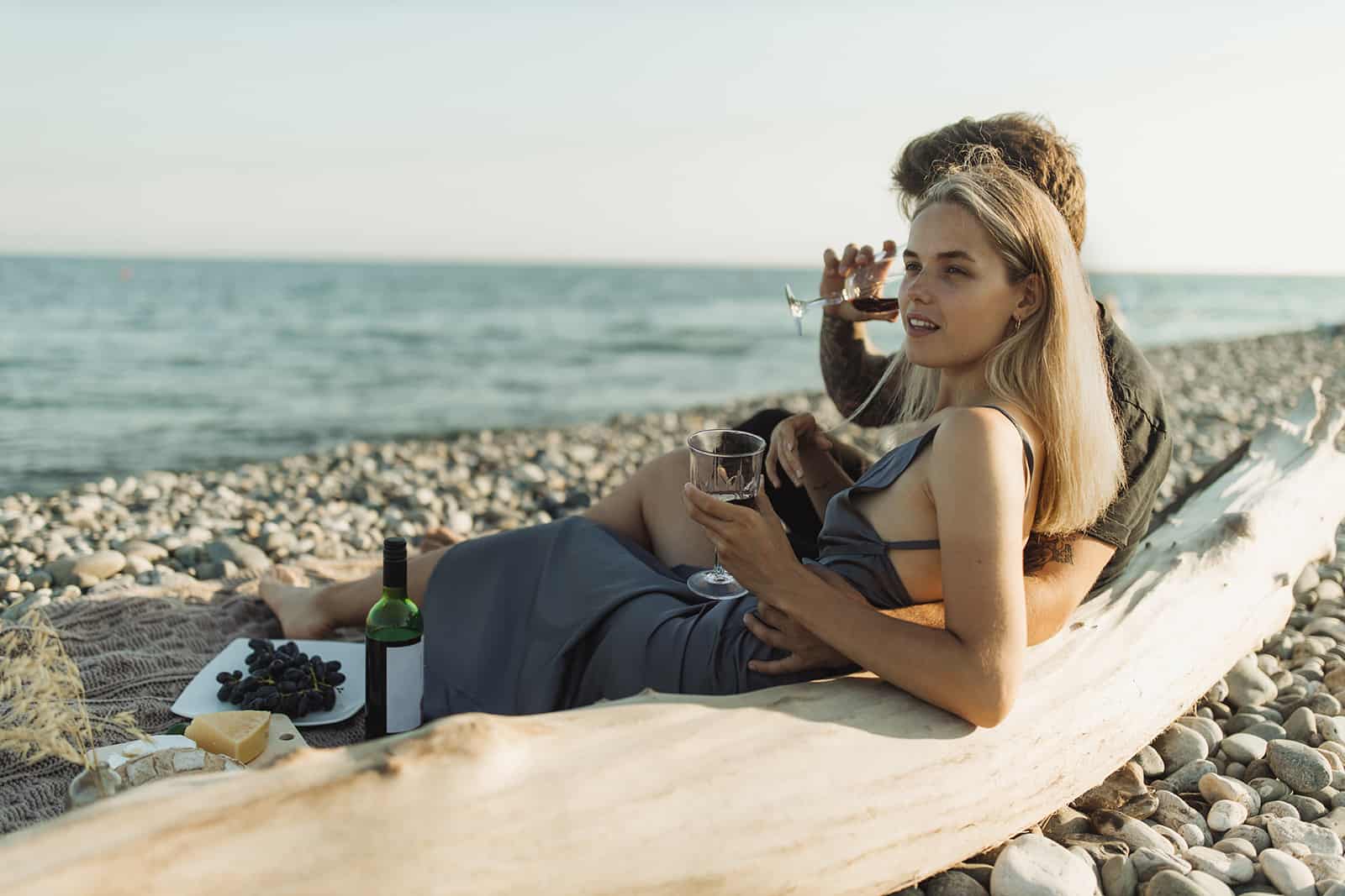 un couple buvant du vin sur un pique-nique à la plage