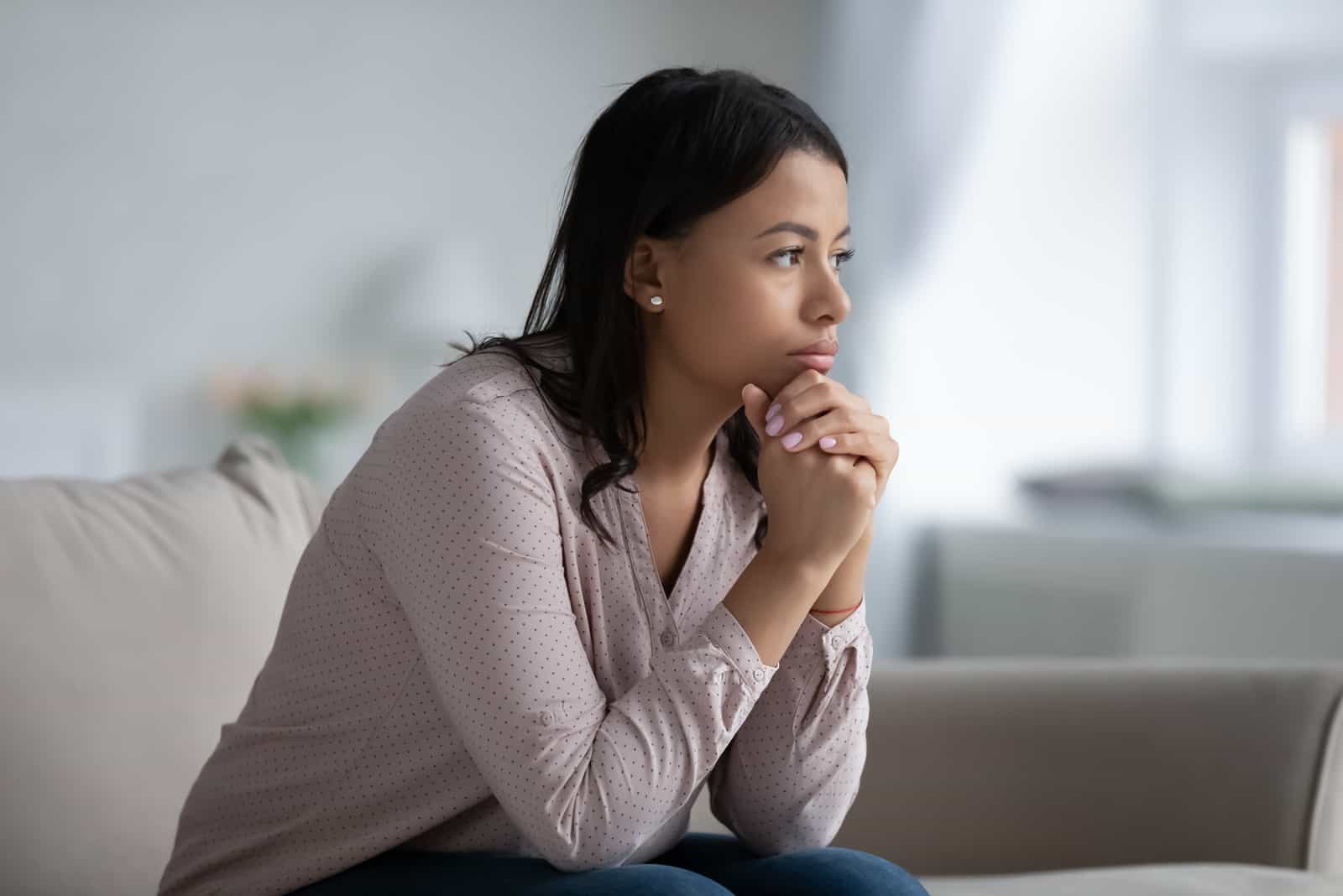 femme assise sur un canapé dans le salon en pensant au problème