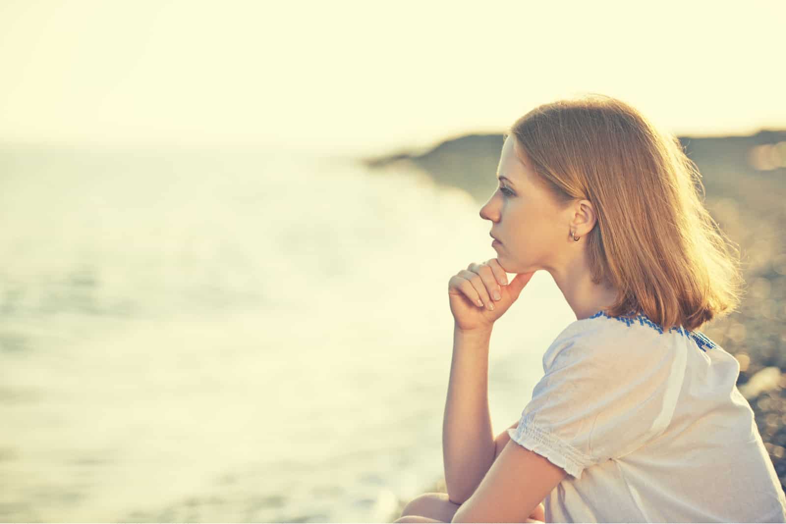 fille triste assise sur la côte sur la plage