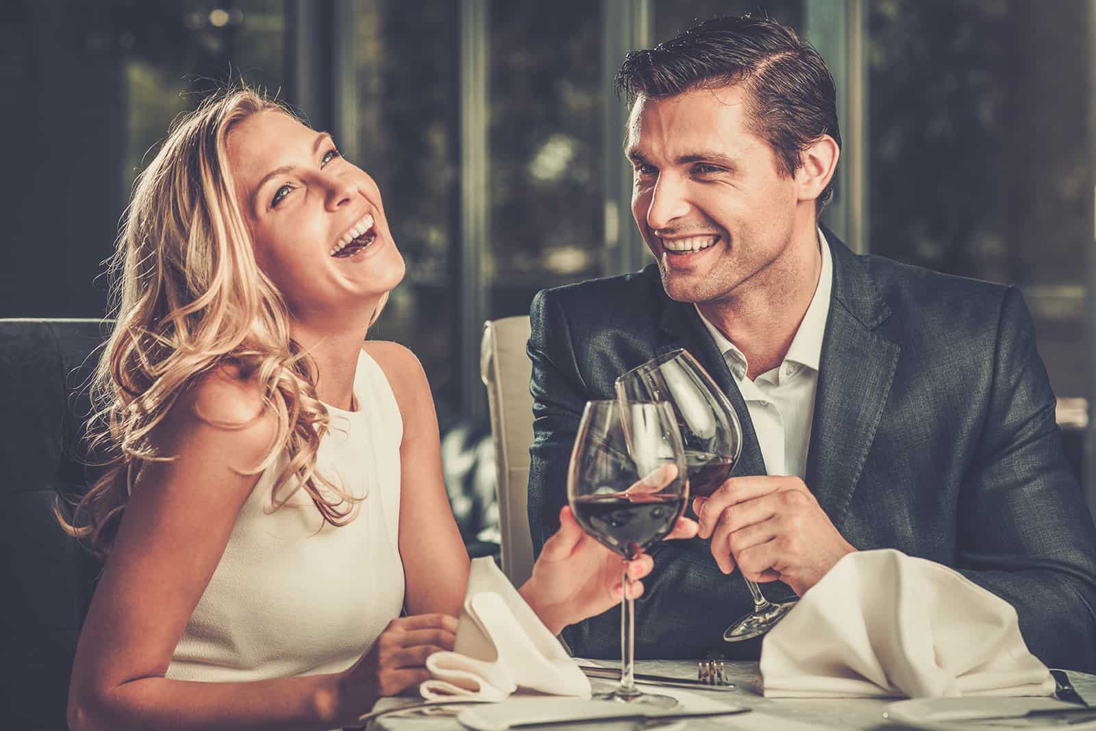 joyeux couple habillé élégant grillage avec du vin dans un restaurant