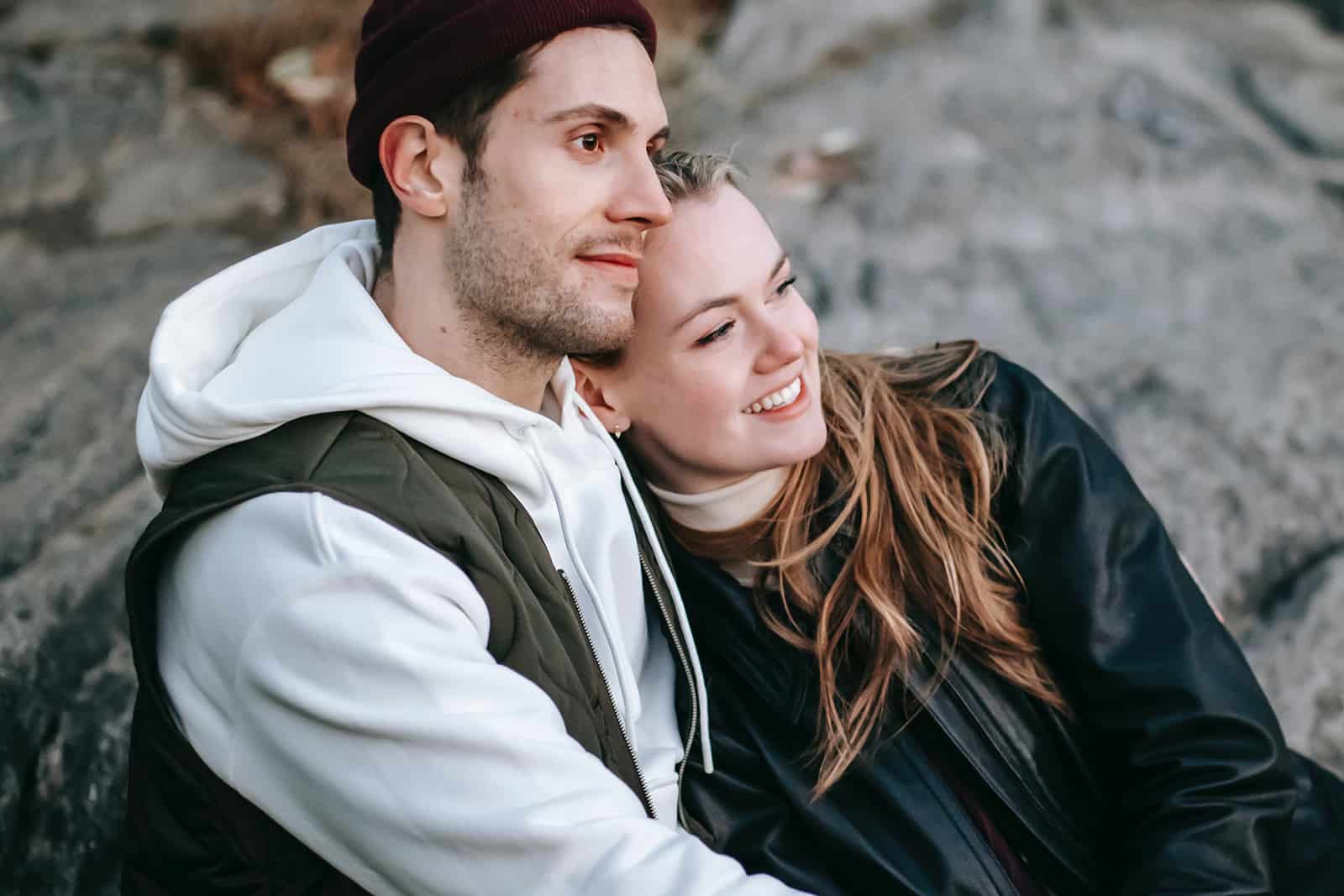 un couple amoureux assis sur le rocher en se serrant dans ses bras