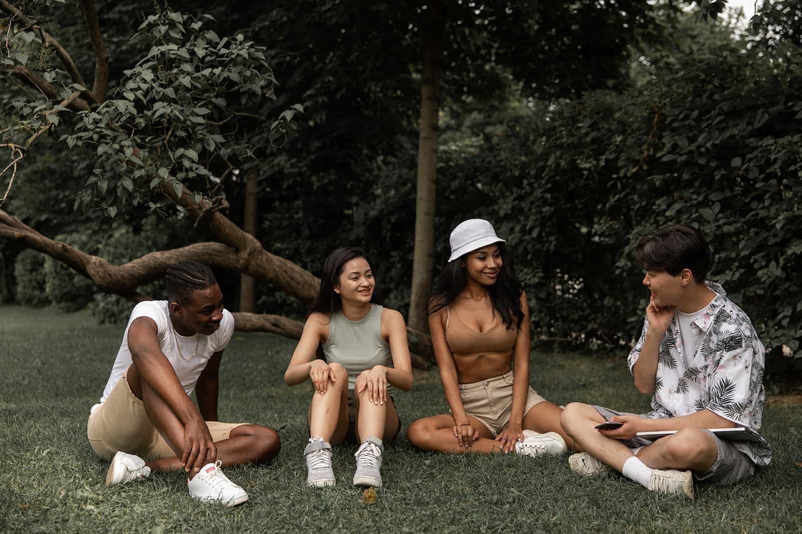 un groupe d'amis assis sur la pelouse et parlant