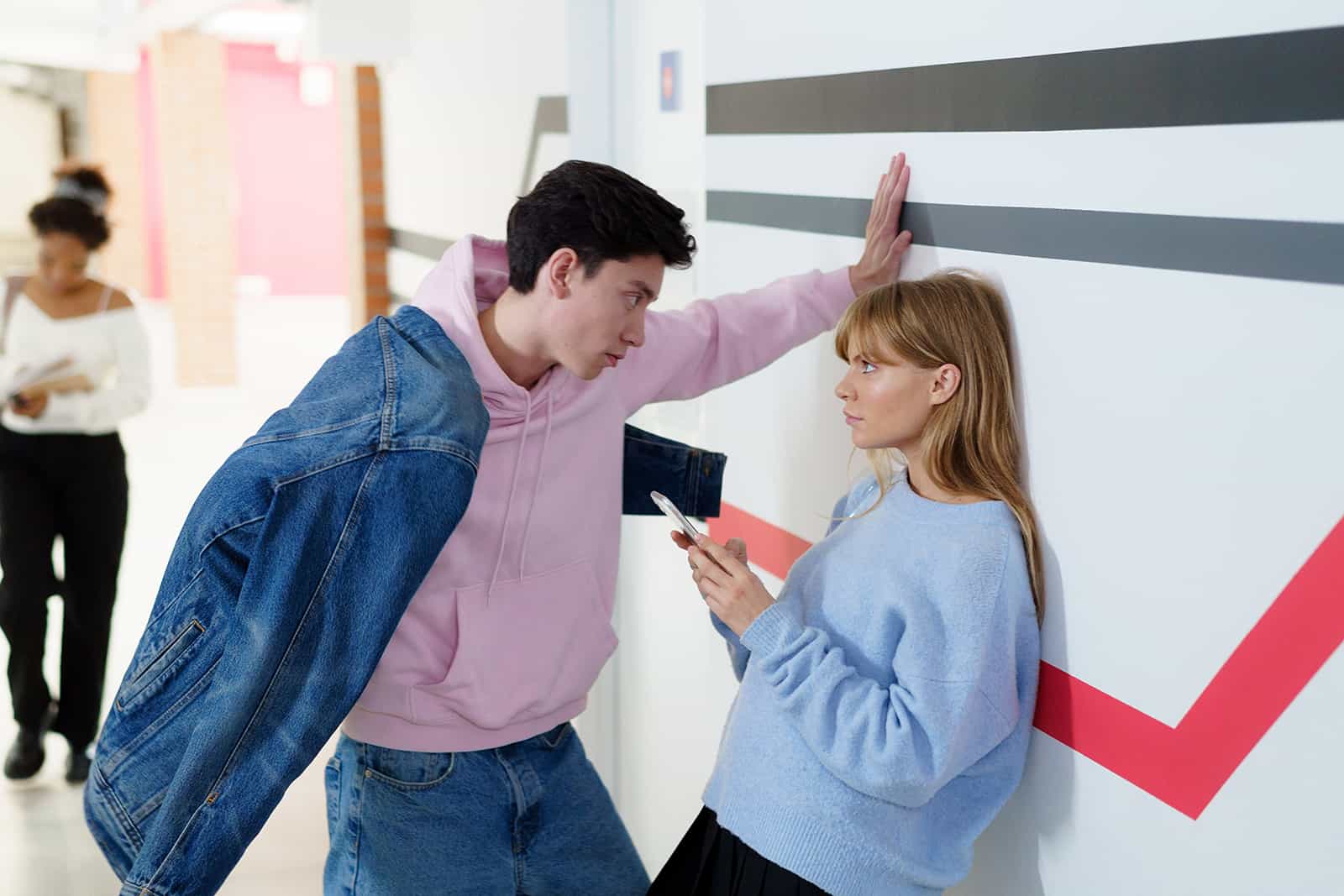 un homme confiant flirter avec une femme sérieuse appuyée sur le mur