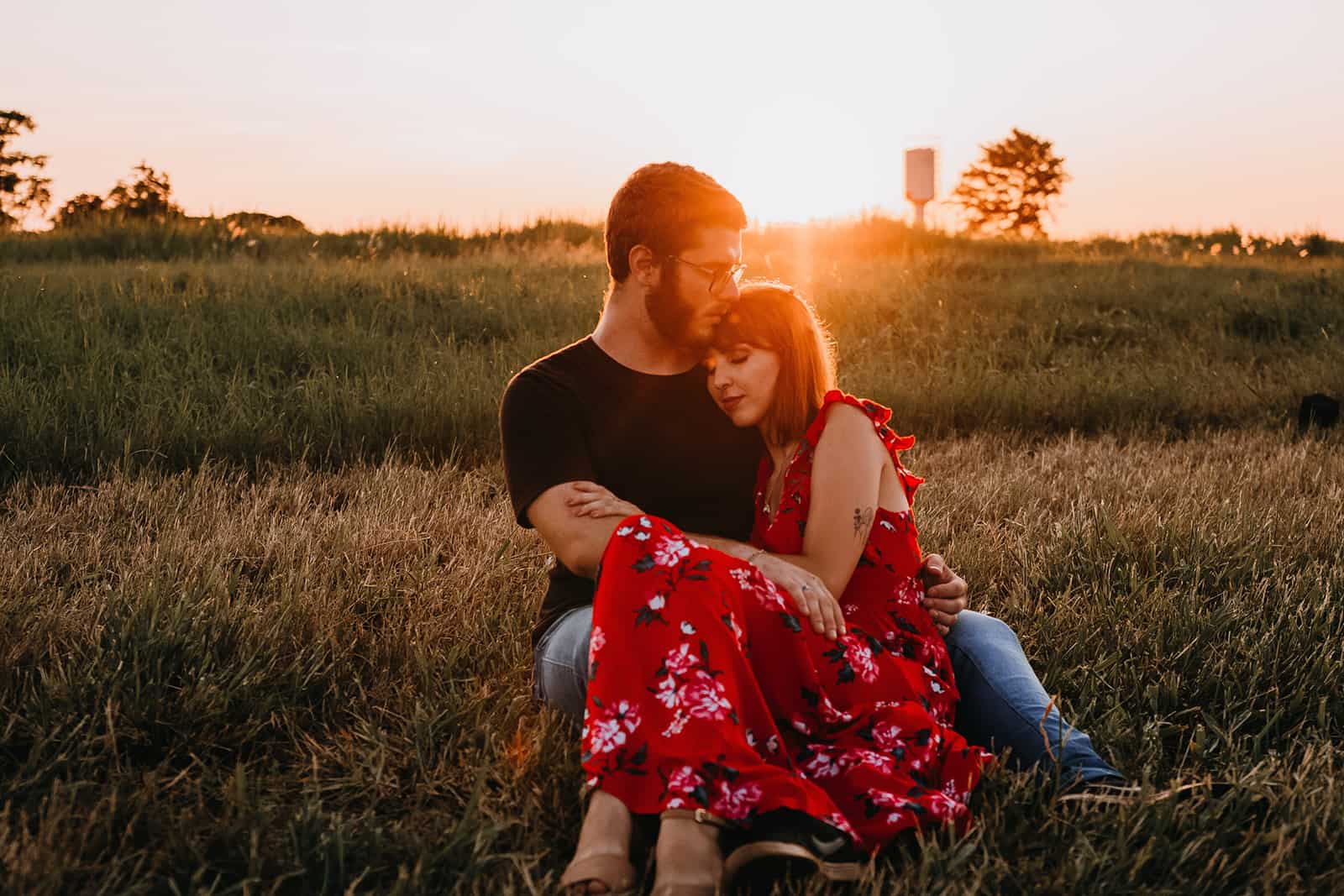 Un homme embrassant sa petite amie alors qu'il était assis ensemble sur le terrain pendant le coucher du soleil