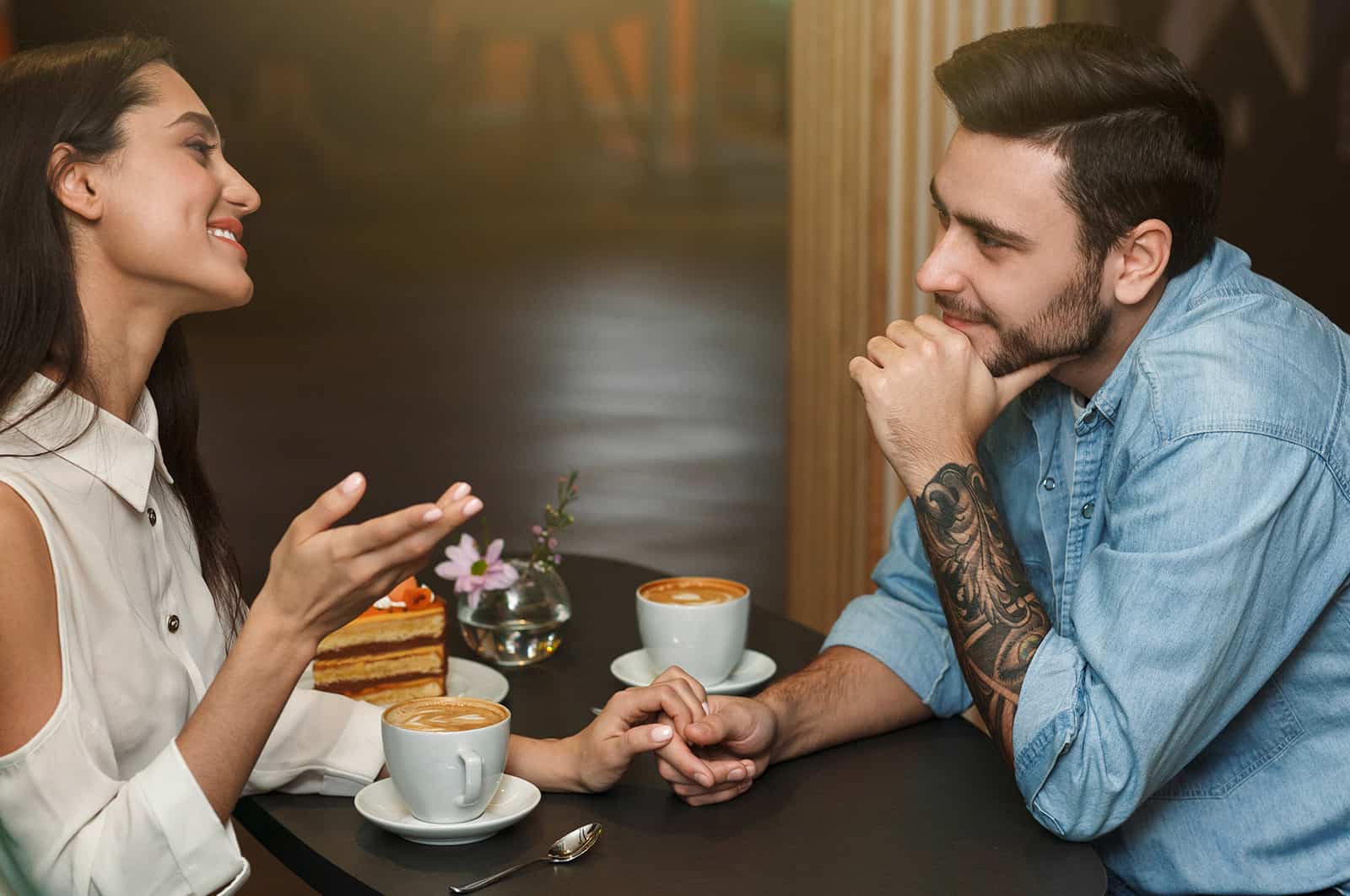 un homme et une femme parlant et s'amusant dans le café et se tenant la main