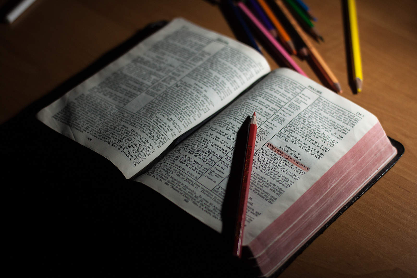 une bible avec un crayon rose dessus sur la table