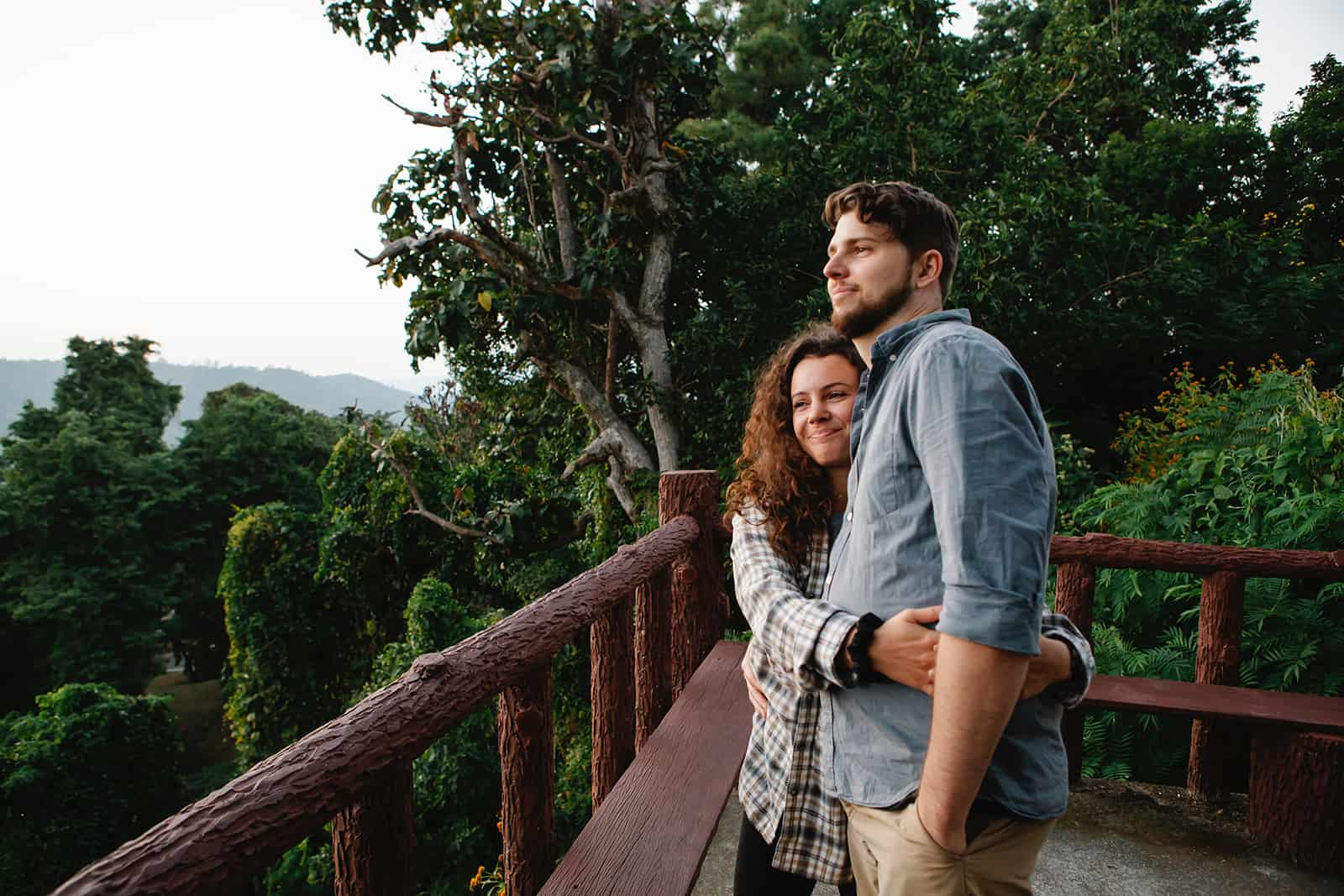 Une femme embrassant son homme debout sur une terrasse en bois et admirant la naturev