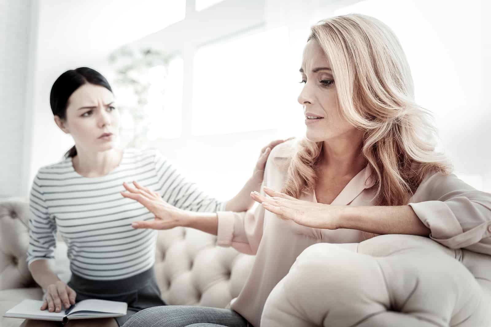 Une femme essayant de communiquer avec des amies bouleversées assis près d'elle sur le canapé