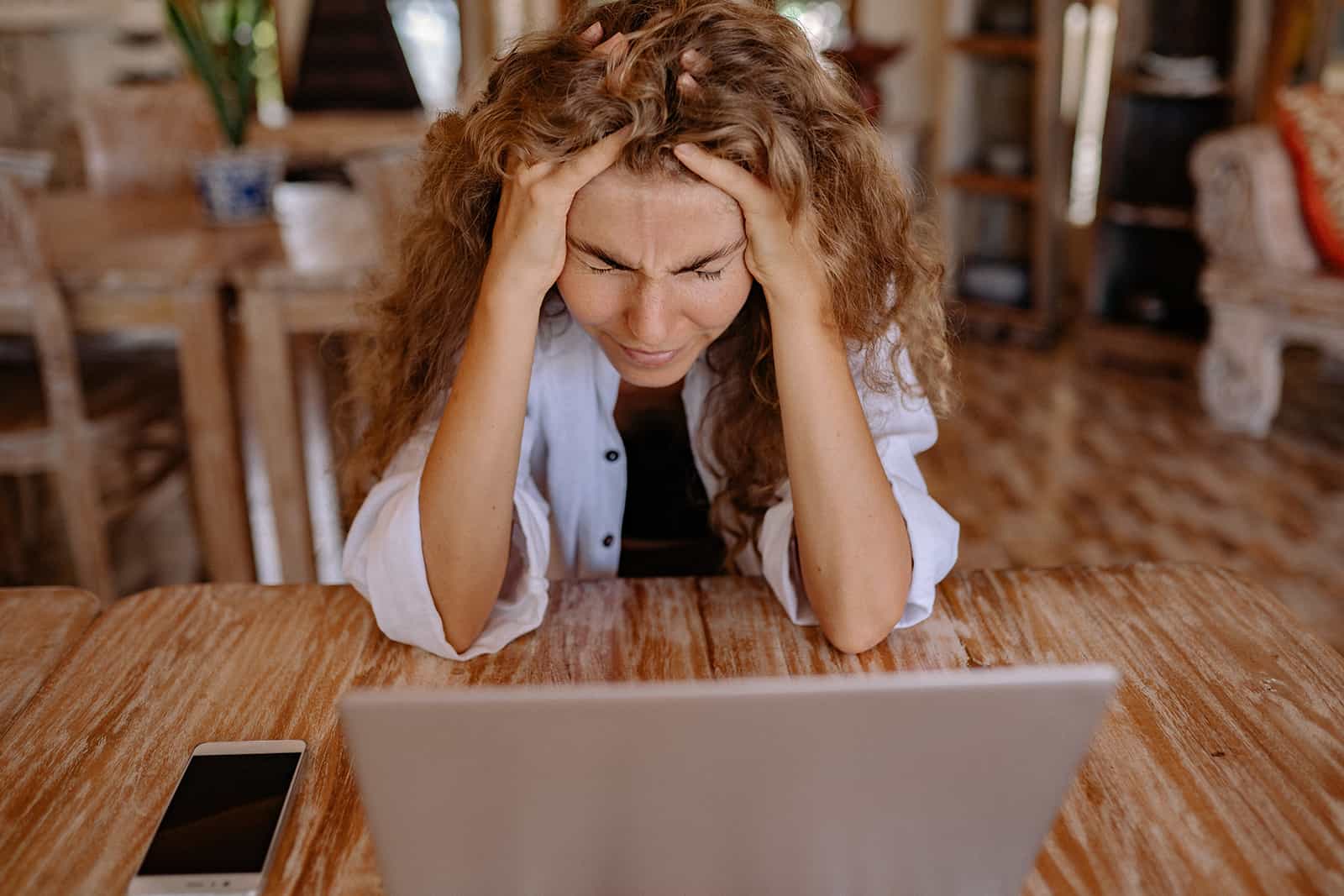 Une femme frustrée touchant la tête avec les mains assis devant un ordinateur portable
