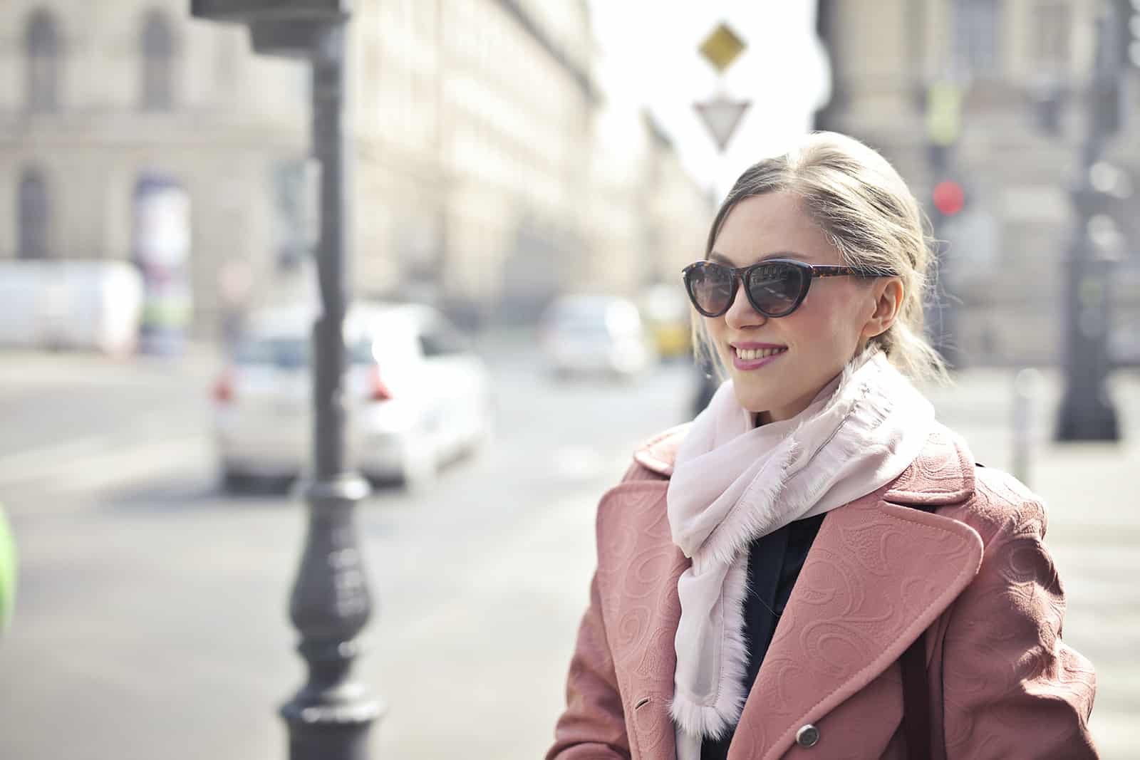 une femme souriante portant des lunettes de soleil debout dans la ville