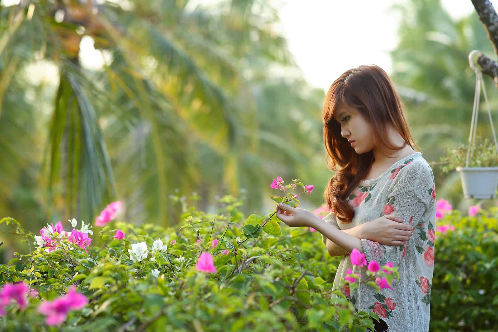 une femme triste debout dans le jardin et toucher des fleurs