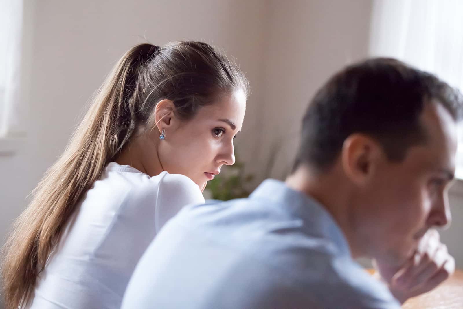 Une femme triste regardant son mari bouleversé alors qu'il était assis près de l'autre